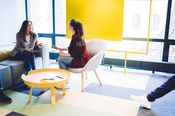 Adult female coworkers having conversation in hallway