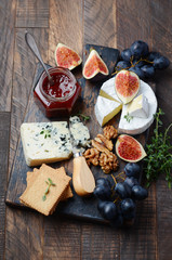 Cheese plate with grapes, figs, crackers, honey, plum jelly, thyme and nuts.