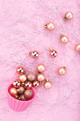 Christmas composition. Christmas baubles, gold decorations on glitter shreds and pink background. Flat lay, copy space, top view. Festive decorations 2020 celebration. New Year. Merry Christmas card. 