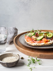 Healthy toast with cream cheese, salmon, fresh cucumber, capers, red onion, black pepper and pea sprouts on plate. Copy space