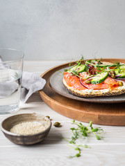 Healthy toast with cream cheese, salmon, fresh cucumber, capers, red onion, black pepper and pea sprouts on plate. Copy space