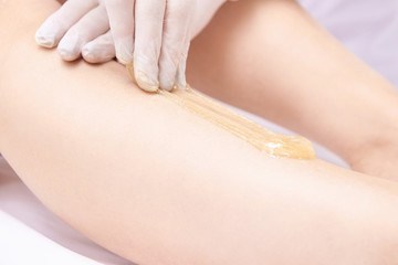 Obraz na płótnie Canvas Hair removal at spa luxury studio. Woman legs wax with shugaring. Hot sugar
