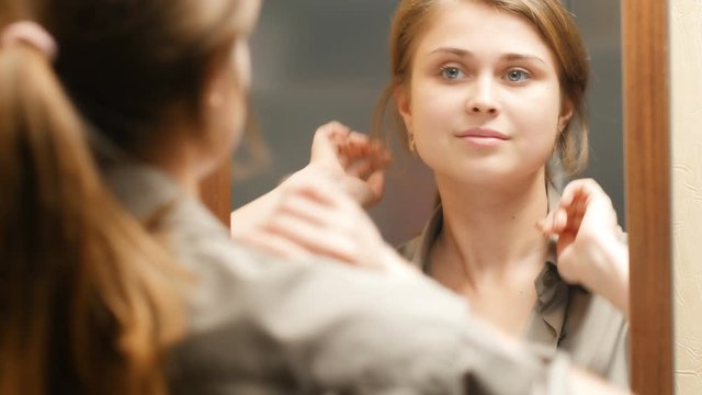 reflection of a cute girl preens herself in front of a mirror at home,beautiful young woman straightens her hair, concept female beauty and fashion