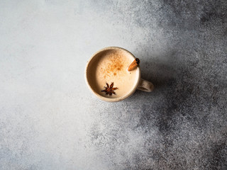 Cup of cappuccino coffee with spices - anise star and cinnamon stick on grey background. Copy space.