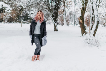 Fototapeta na wymiar Young Blonde Woman in Gray Sweater and Black Jacket is Enjoying Winter
