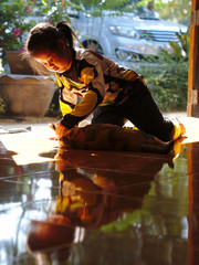  An Asian girl is playing with her favorite cat at home, with the beautiful sun shining in.