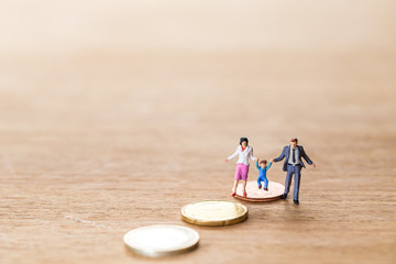 miniature family standing on euro coins over blurred wooden   background, Image for money management concept.