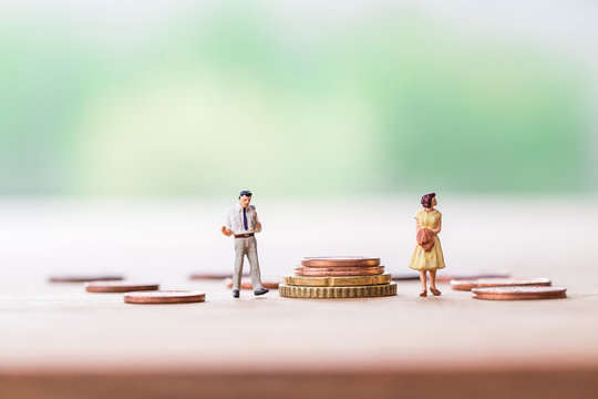 selective focus of miniature angry woman with miniature man and  stack coins over blurred green garden background  for Asset management after divorce concept.