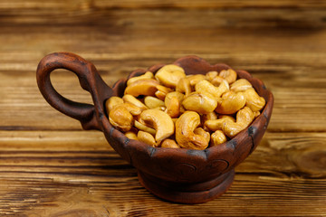 Ceramic bowl with roasted cashew nuts on a wooden table