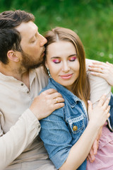 Portrait of a couple in love. The guy kisses the girl on the temple and hugs her. Valentine's day. Love and happiness in a relationship