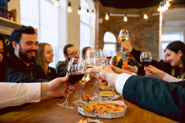Happy co-workers celebrating while company party and corporate event. Young caucasian people in business attire cheering, laughting. Concept of office culture, teamwork, friendship, holidays, weekend.