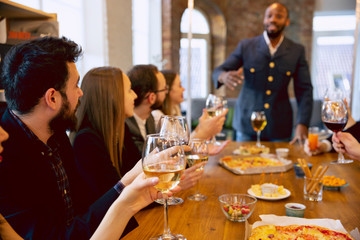 Happy co-workers celebrating while company party and corporate event. Young caucasian people in business attire cheering, laughting. Concept of office culture, teamwork, friendship, holidays, weekend.