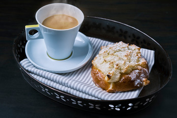 pao de deus, typical Portuguese dessert and a coffee with a spoon ver a blackboard and a iron tray