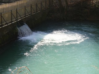 Water cascades down an outlet from a spring through a small dam