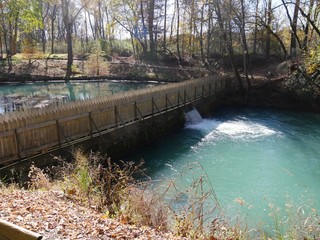 Wide view ofa wooden fence with water flowing down a small dam in a spring