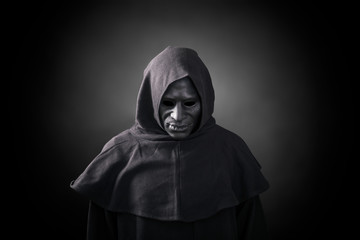 Scary figure in hooded cloak with mask 