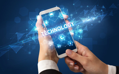 Female hand holding smartphone with TECHNOLOGY inscription, modern technology concept
