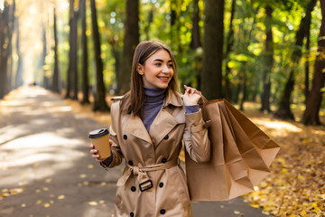 Young woman walking with shopping bag and hot coffee in city center