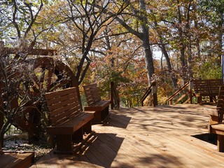 Wide shot of a wooden walkway with benches and working waterwheel at a park