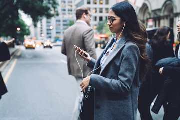 Pretty young female walking down street and listening to music