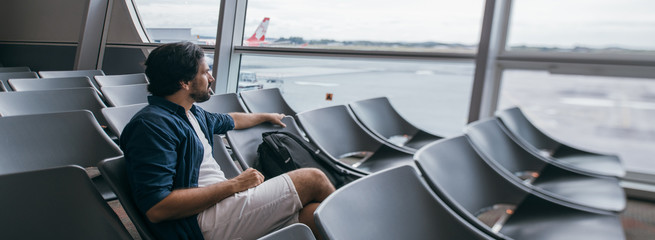 A man sits in a waiting room at the gate at the airport.