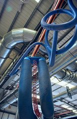 Plastic ribbed air conditioning airflow pipes and tubing sucking dust and industrial particles out of wood and metal cutting machines. Keeping the air and workplace clean and free from pollution