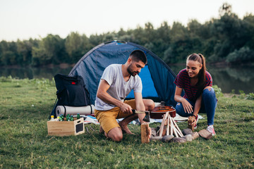 friends having fun camping outdoor , preparing camping fire