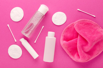 make up remove products, micellar water, face cleaning cloth, cleansing milk and gel with cotton pads on pink background