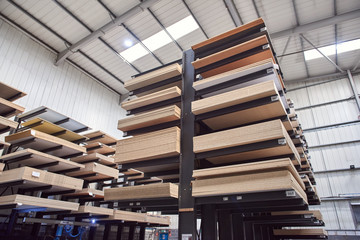 A large industrial racking in a woodworking diy factory,  holding and storing various wooden laminate plywood chipboard boards. wood work carpentry and diy unsustainable building materials.