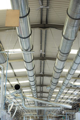 Industrial metal air flow and air conditioning pipes on the ceiling of an industrial factory. keeping the air fresh and clean for health and safety purposes. Healthy working environment for workers