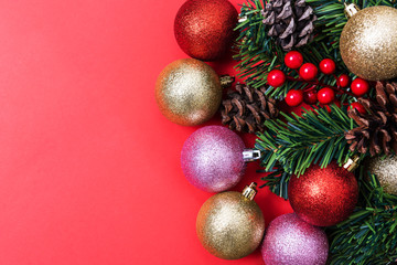 Obraz na płótnie Canvas Christmas Decorations on red background, Christmas border with cedar leaf, pine cones and baubles.