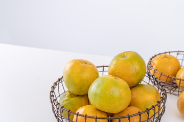 Beautiful peeled tangerines in a plate and metal basket isolated on bright white clean table in a modern contemporary kitchen island, close up.