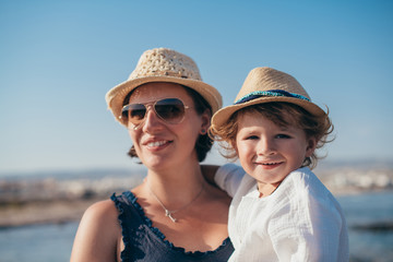 Portrait of a happy mom with a little son on a trip near the sea.