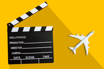 Movie clapper board with white airplane model on yellow background
