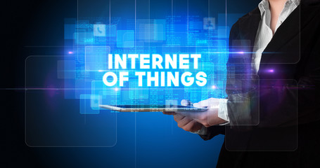 Young business person working on tablet and shows the inscription: INTERNET OF THINGS