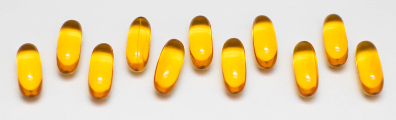 Capsules with fish oil on a white background are laid out in a row. The use of vitamin D, omega-3.