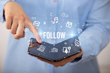 Businessman holding a foldable smartphone with FOLLOW inscription, social media concept