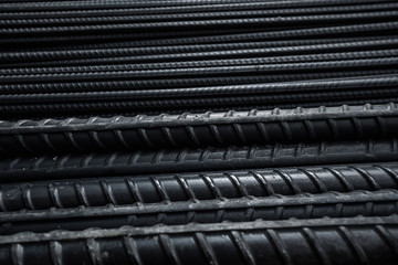 Building armature in the warehouse of metallurgical products or on construction site. Stack of heavy metal reinforcement bars with periodic profile texture. Steel construction armature.
