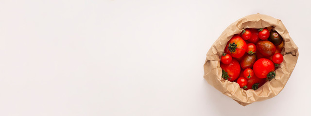 Organic red tomatoes on white background in eco shopping bag