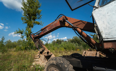 Old excavator in the field in sunny day.
