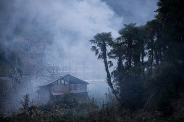 Smoke from burning agricultural waste billows over small shack in rural Japanese mountains