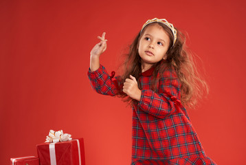 little girl surrounded by New Year's gifts on a red background