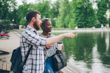 Diverse couple talking near pond in park