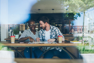 Multiracial couple laughing and planning summer trip at cafe