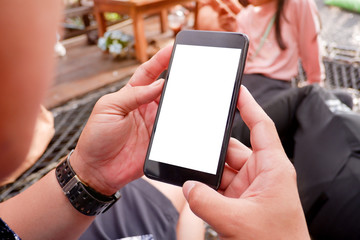 Mockup picture of business woman’s hands holding smart phone with white blank screen in modern place.