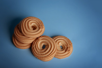 Round shortbread cookie lies on a blue background. View from above.