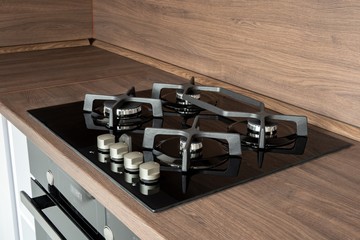 A modern gas cooker with ceramic hob, electric oven and a dark brown wooden kitchen ready for cooking a meal
