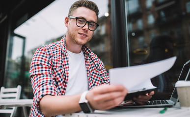 Bright handsome male reviewing blank at outside of cafe