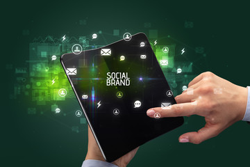 Businessman holding a foldable smartphone with SOCIAL BRAND inscription, social networking concept