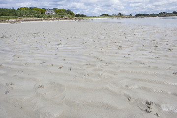 Low tide at a beach at the coast of Brittany, blue sky with clouds
